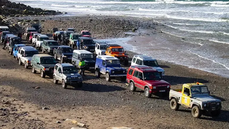 multiple 4 by 4 vehicles driving on the foreshore.