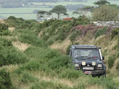 Land rover driving on a small track in the country.