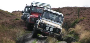 Three Land Rovers driving down a green lane.